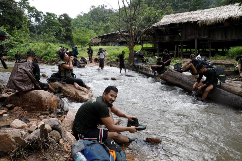 Mr Maung washes his shoes in a river (Reuters)