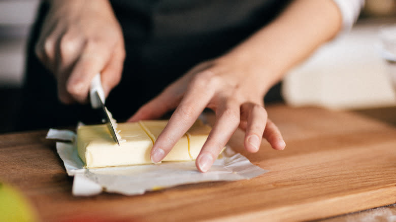 person cutting butter on board