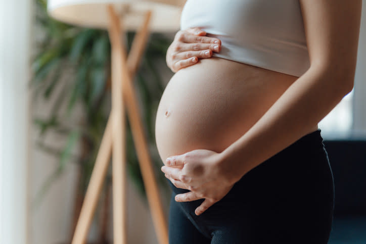 A pregnant person holding their belly