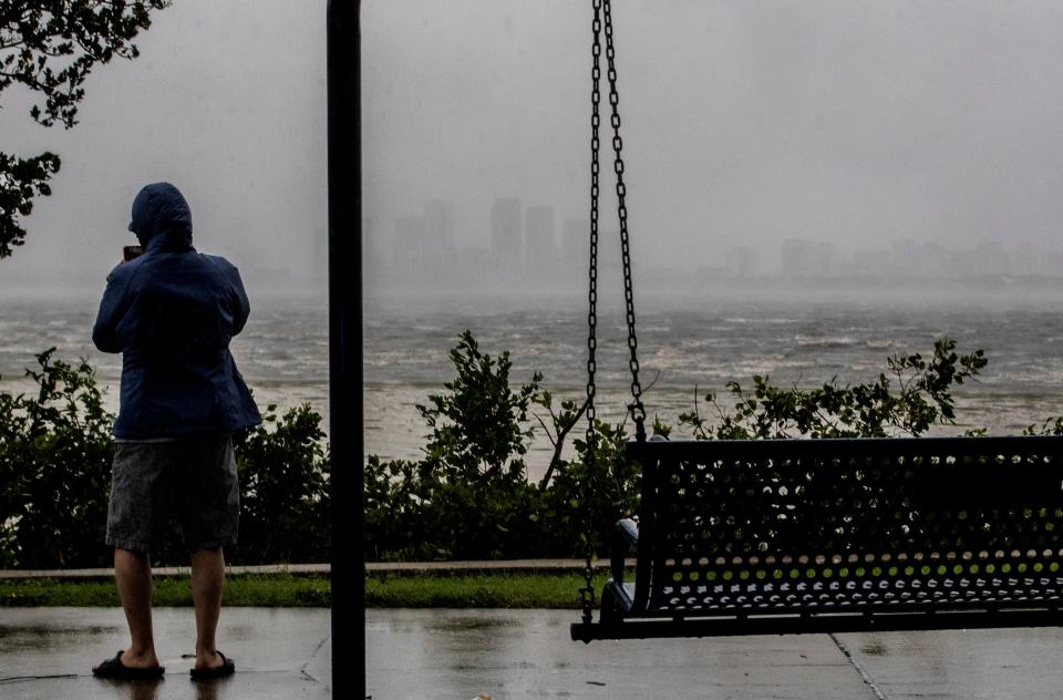 One sightseer witnesses the receding waters of Tampa Bay because of low tide and tremendous winds from Hurricane Ian with downtown in the distance in Tampa, Florida, Wednesday, 28 September 2022 (AP)