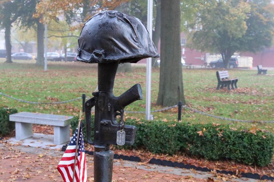 At the Vietnam War memorial in Beaver's Quay Square, a display shows a military rifle with a helmet and dog tags. The tags are engraved with the phrase "Never Forget" and are dedicated to veterans in Beaver County.