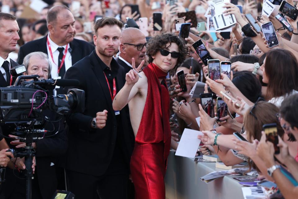 Picture this: Timothée Chalamet posing with fans (and their phones) on the red carpet at Venice Film Festival in 2022 (Getty)