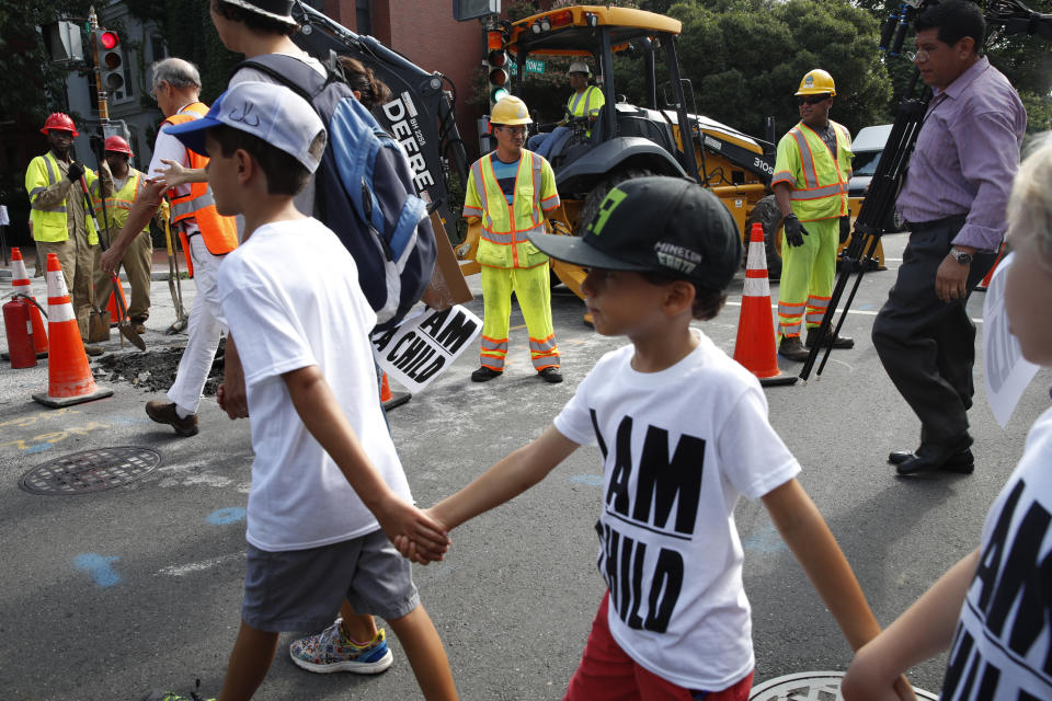 Construction workers watch as children hold hands during a march in protest of the separation of immigrant families, Thursday, July 26, 2018, on Capitol Hill in Washington. The Trump administration faces a court-imposed deadline Thursday to reunite thousands of children and parents who were forcibly separated at the U.S.-Mexico border, an enormous logistical task brought on by its "zero tolerance" policy on illegal entry. (AP Photo/Jacquelyn Martin)