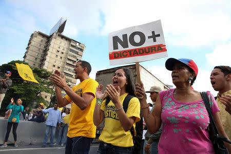 Opposition supporters holding a placard that reads, "No more dictatorship" shout slogans as they block a highway during a protest against Venezuelan President Nicolas Maduro's government in Caracas, Venezuela March 31, 2017. REUTERS/Carlos Garcia Rawlins