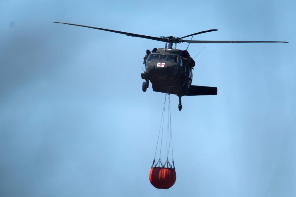 A Tennessee National Guard Blackhawk helicopter carries nearly 600 gallons of water to the Cold Springs Hollow Road fire in Seymour, Tenn. on Sunday, April 3, 2022. 