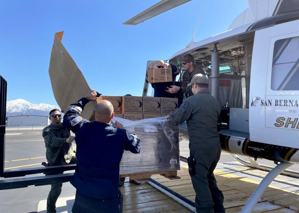 Emergency personnel load boxes onto a helicopter.