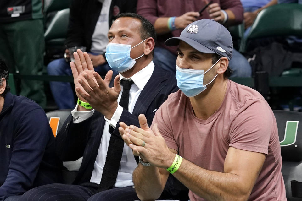 Former MLB player Alex Rodriguez, left, sits with former NFL wide receiver Eric Decker, right, during the first half of an NCAA college basketball game between Miami and North Carolina, Tuesday, Jan. 18, 2022, in Coral Gables, Fla. (AP Photo/Lynne Sladky)