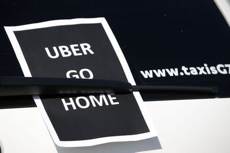 A leaflet which reads "Uber go home" is seen on a taxi as striking French taxi drivers block the traffic on the Paris ring road during a national protest against car-sharing service Uber, in Paris, France, June 25, 2015. REUTERS/Charles Platiau
