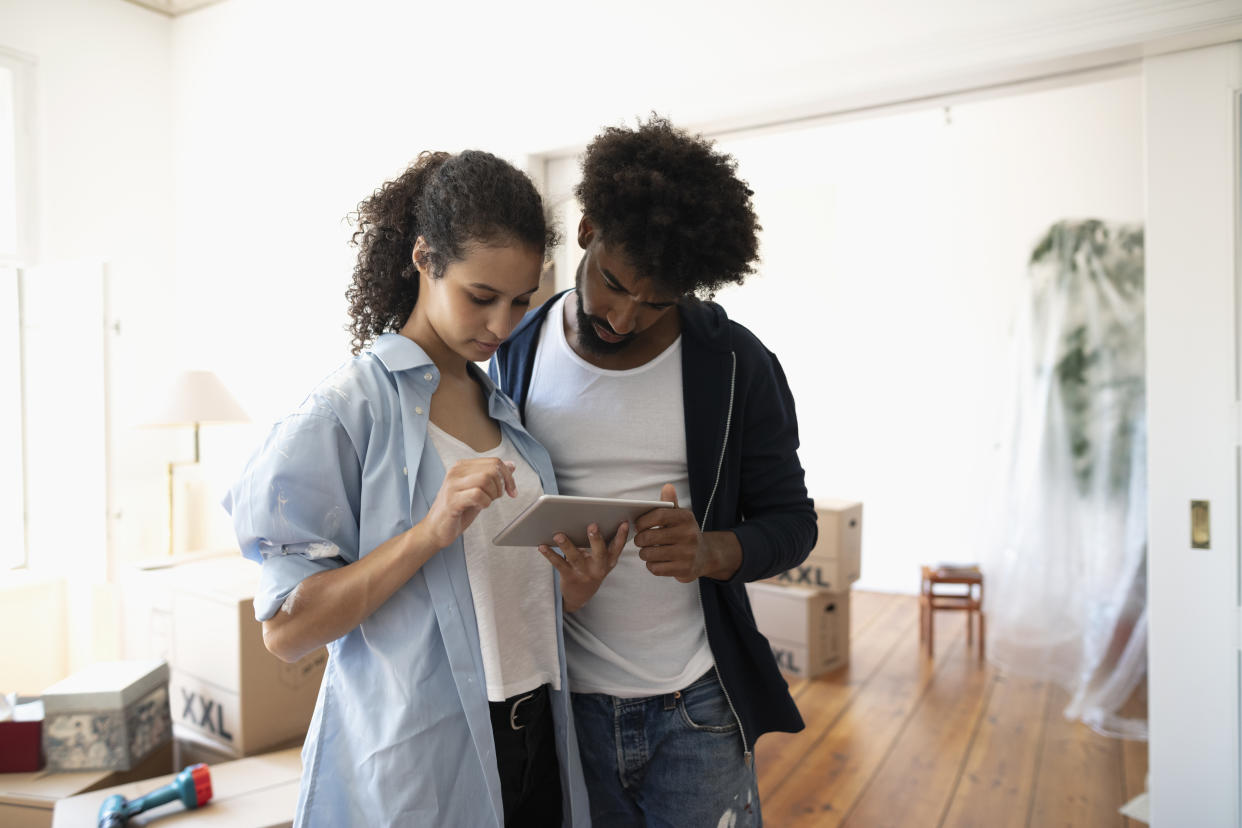 Couple moving into new home, using digital tablet