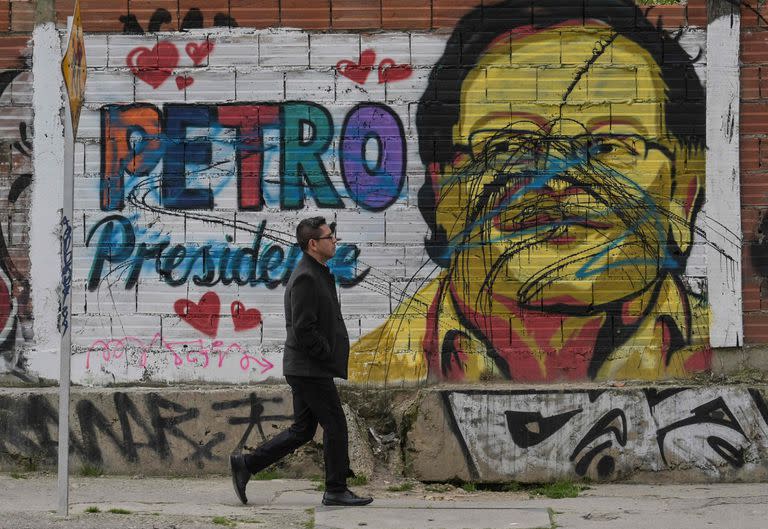 Un hombre camina frente al mural de Petro presidente