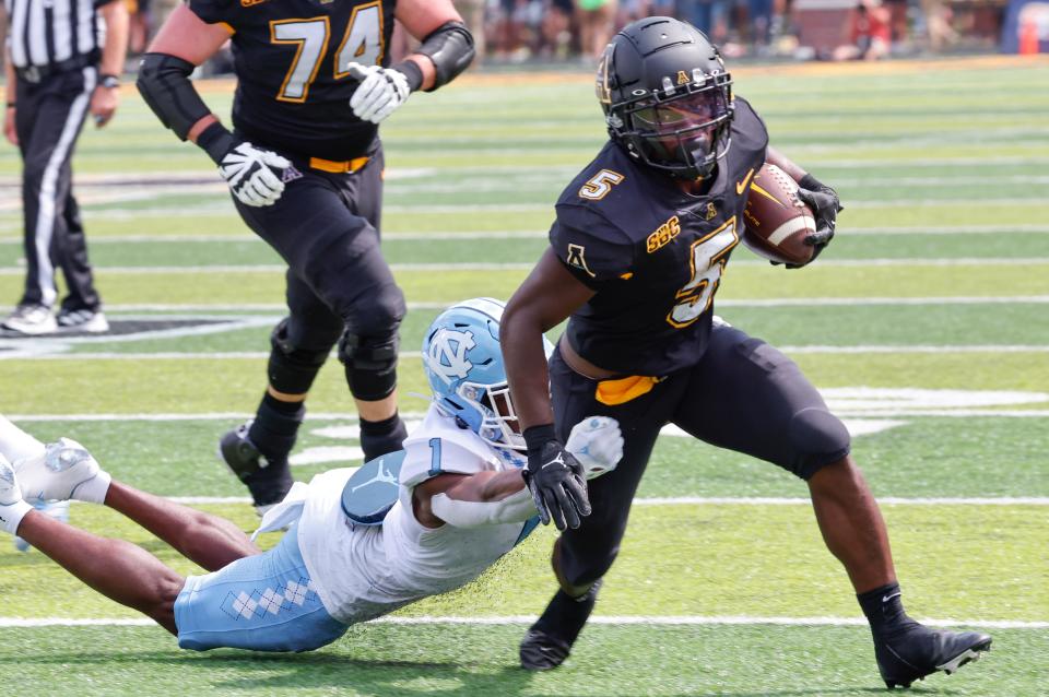 Appalachian State running back Nate Noel (5) is tackled by North Carolina defensive back Tony Grimes (1) during the second half of an NCAA college football game, Saturday Sept. 3, 2022, in Boone, N.C. (AP Photo/Reinhold Matay)