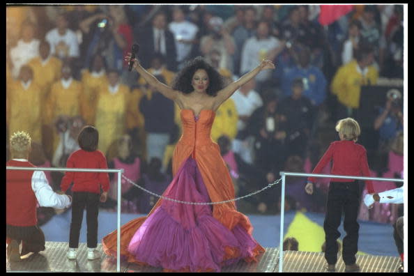 <div class="caption-credit"> Photo by: Getty Images/Al Bello</div>Four outfit changes, including this orange-and-purple strapless gown, along with a dramatic exit via helicopter (the halftime theme was "Take Me Higher"), made Diana Ross's 1996 medley performance a winner.