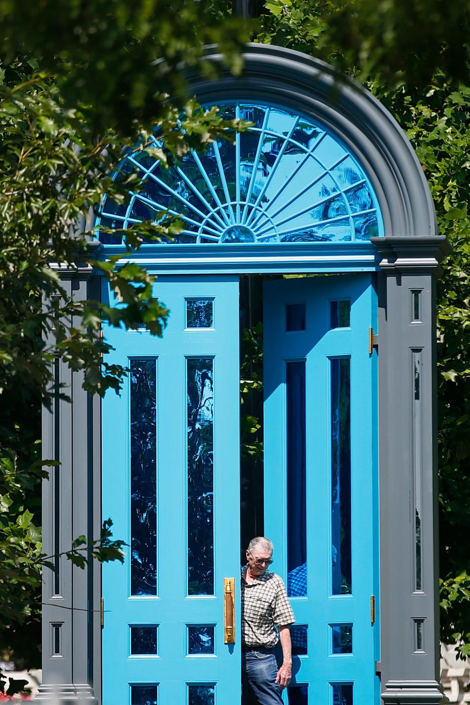 A man emerges from the seventeen foot tall doorway art piece 'Threshold' installed at Custom House Square in New Bedford.