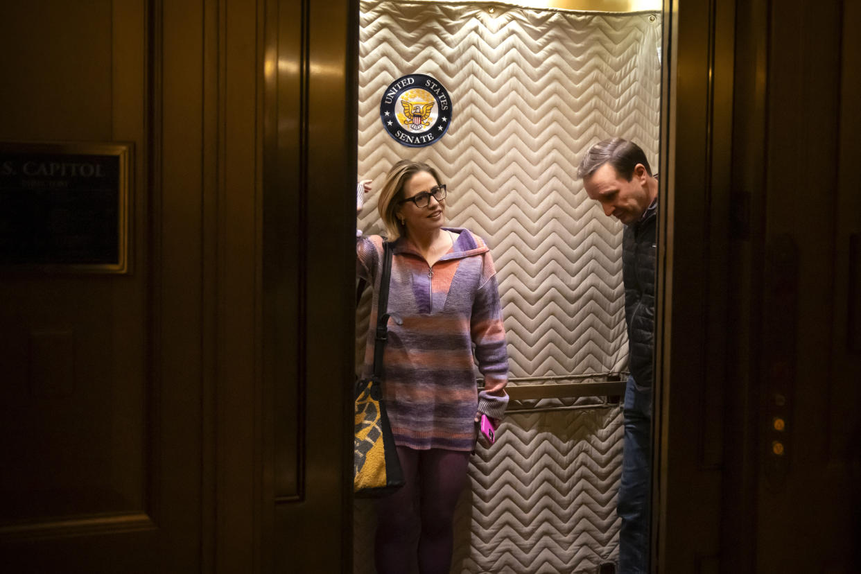 Sen. Kyrsten Sinema, I-Ariz., left, and Sen. Chris Murphy, D-Conn., stand in an elevator as they arrive for closed-door negotiations on a border security deal at the Capitol, Sunday, Dec. 17, 2023, in Washington. Negotiators are rushing to reach a U.S. border security deal that would unlock President Joe Biden's request for billions of dollars worth in military aid for Ukraine and national security. (AP Photo/Mark Schiefelbein)