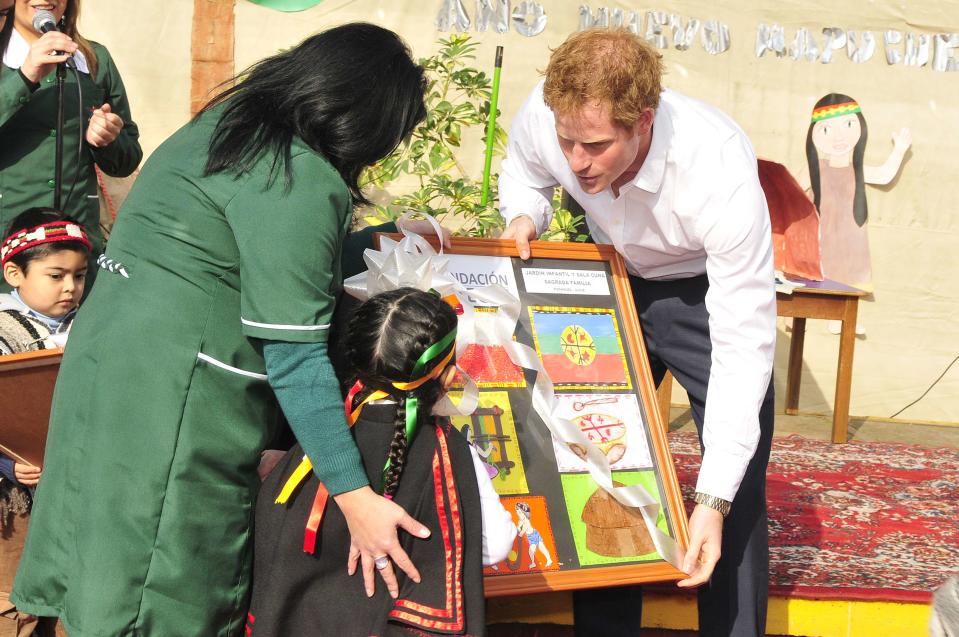Britain's Prince Harry receives a gift from a Mapuche (Chilean Indian) child during a visit to Integra Foundation, a daycare center for at-risk children, in Santiago