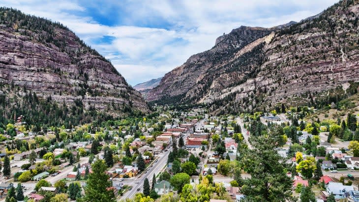 Aerial view of downtown Ouray, Colorado surrounded by autumn foliage forest from lookout point on Million Dollar Highway
