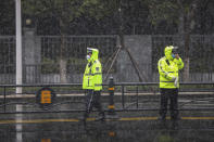 Policemen wearing face masks wait to direct traffic along a street during a snowfall in Wuhan in central China's Hubei Province, Saturday, Feb. 15, 2020. China reported 143 virus deaths and a dip in new cases Saturday while the government announced new anti-disease measures as businesses reopen following sweeping controls that idled much of the economy. (Chinatopix via AP)