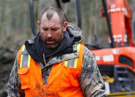 A weary searcher bows his head as he walks out of the west side of the mudslide site with a small saw on Highway 530 near mile marker 37  in Arlington, Wash., on Sunday, March 30, 2014. Periods of rain and wind have hampered efforts the past two days, with some rain showers continuing today. Last night, the confirmed fatalities list was updated to 18, with the number of those missing falling from 90 to 30. (AP Photo/Rick Wilking, Pool)