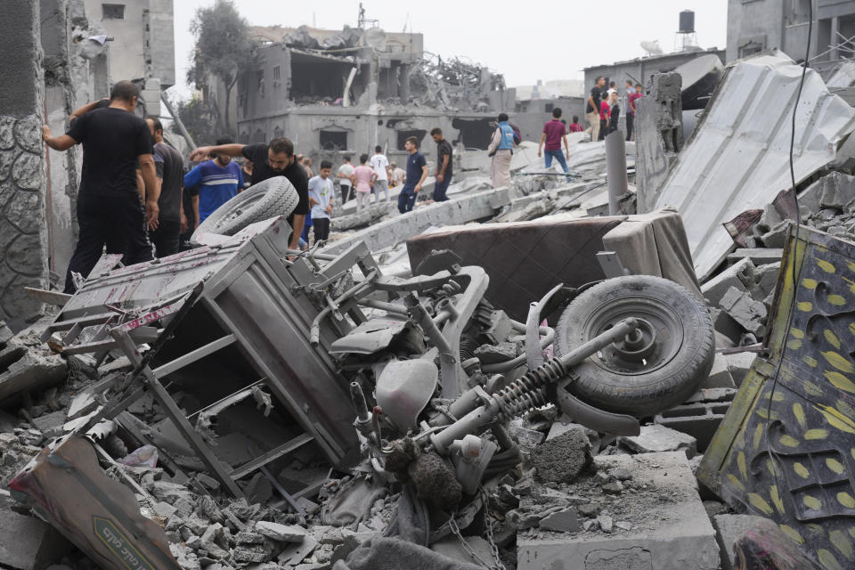 Palestinians walk about buildings destroyed in the Israeli bombardment in the Nusseirat refugee camp in the Gaza Strip on Sunday, Oct. 29, 2023. (AP Photo/Hatem Moussa)