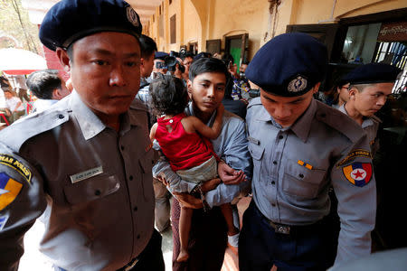 Detained Reuters journalist Kyaw Soe Oo is escorted by police as he carries his daughter during a lunch break at a court hearing in Yangon, Myanmar February 28, 2018. REUTERS/Stringer
