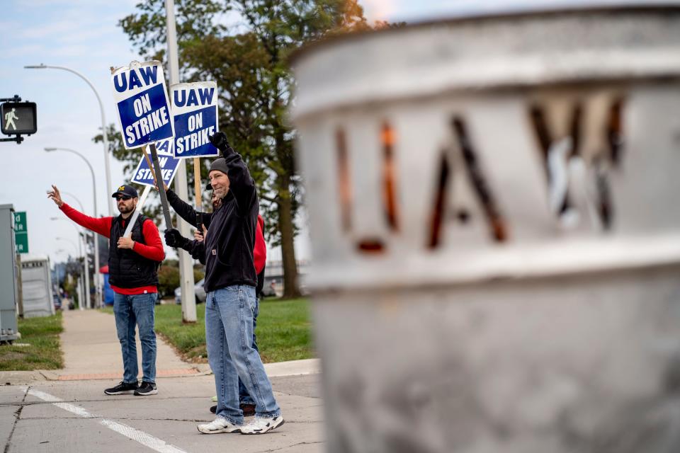 Wood burns in a barrel as workers stand outside of the Ford Michigan Assembly Plant in Wayne while on strike on Thursday, Oct. 12, 2023.