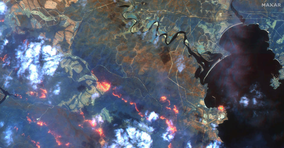 This satellite photo provided by Maxar Technologies shows wildfires spreading in the area south of Eden and Twofold Bay, shown in black, in New South Wales state of Australia, Sunday, Jan. 12, 2020. (Satellite image ©2020 Maxar Technologies via AP)