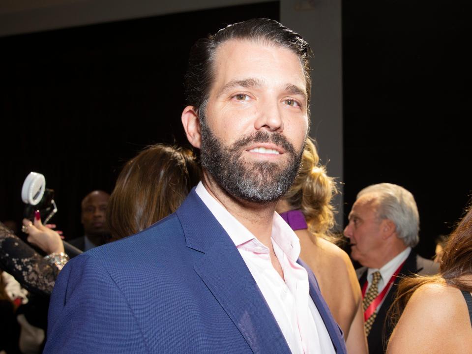 Trump Jr. smiling in a beard and suit.