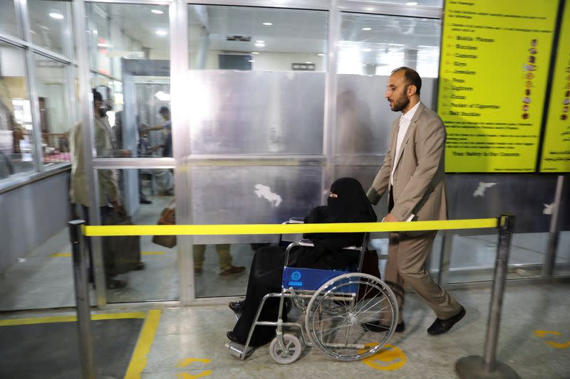 A man helps a relative with the wheelchair at the departures lounge to board the first commercial flight to be operated from Sanaa Airport, in Sanaa