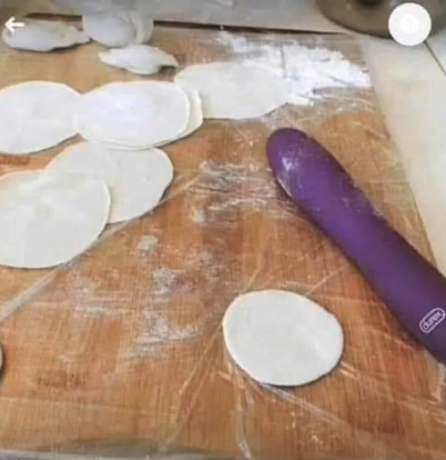 Several circular dough pieces on a floured wooden board near a purple silicone adult toy