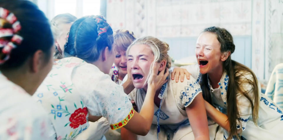 A group of women in traditional dresses comforts another woman who is crying