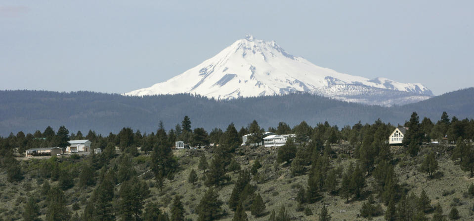 FILE - Mount Jefferson looms over off-grid homes at the Three Rivers Recreational Area, in Lake Billy Chinook, Ore., on April 26, 2007. Everyone in this community lives "off the grid", part of a growing number of homeowners now drawing all their power from solar, wind, propane and other sources. (AP Photo/Don Ryan, File)