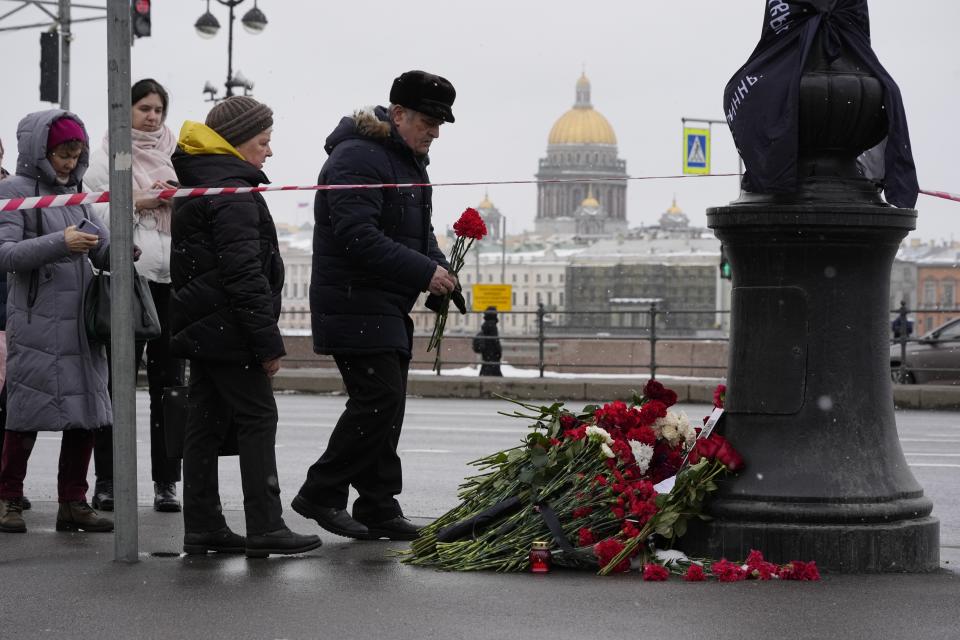 People lay flowers near the side of an explosion at the "Street Bar" cafe with the St. Isaac's Cathedral in the background in St. Petersburg, Russia, Monday, April 3, 2023. An explosion tore through a cafe in Russia's second-largest city, killing a well-known military blogger and strident supporter of the war in Ukraine. Some reports said a bomb was embedded in a bust of the blogger that was given to him as a gift. Russian officials said Vladlen Tatarsky was killed Sunday as he led a discussion at the cafe in the historic heart of St. Petersburg. (AP Photo/Dmitri Lovetsky)