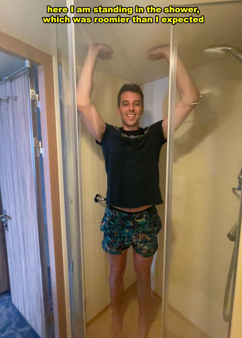 Man in shorts smiling inside a spacious shower, with text overlay about the shower's size