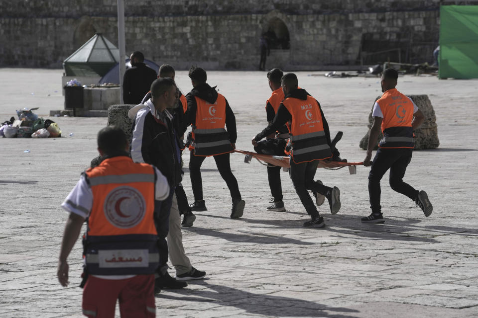 Palestinian medics evacuate a person wounded in clashes between protesters and Israeli police at the Al Aqsa Mosque compound, in Jerusalem's Old City, Friday, April 22, 2022. Israeli police in full riot gear stormed the sensitive Jerusalem holy site sacred to Jews and Muslims on Friday after Palestinian youths hurled stones at a gate where they were stationed. (AP Photo/Mahmoud Illean)