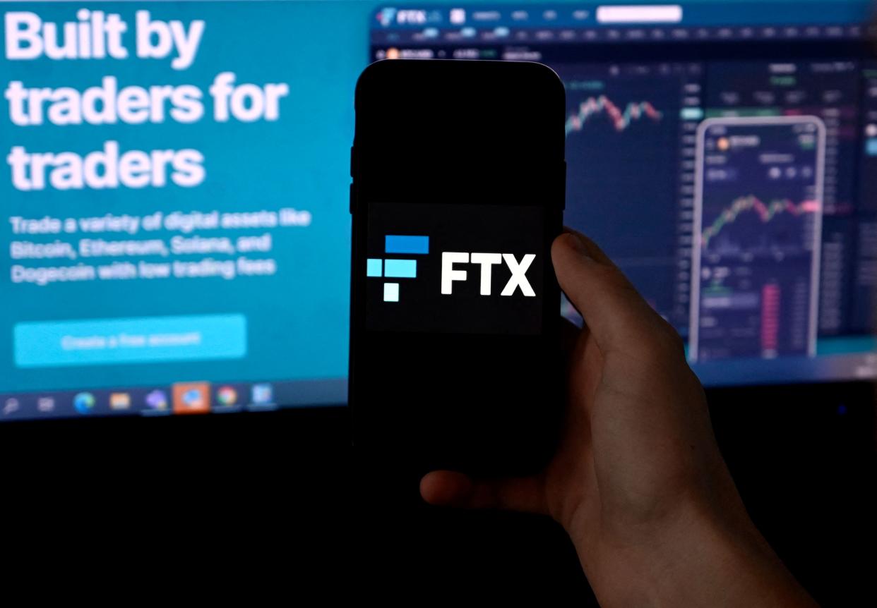 This illustration photo shows a smart phone screen displaying the logo of FTX, the crypto exchange platform, with a screen showing the FTX website in the background in Arlington, Virginia on February 10, 2022. - Sam Bankman-Fried donned a suit and tie this week, abandoning his preferred hoodie and dark T-shirt for a hearing before US Senators.  The lawmakers had summoned the 29-year-old multi-billionaire on Wednesday to discuss the regulation of digital assets in his capacity as co-founder and CEO of the cryptocurrency exchange platform FTX (Photo by OLIVIER DOULIERY / AFP) (Photo by OLIVIER DOULIERY/AFP via Getty Images)