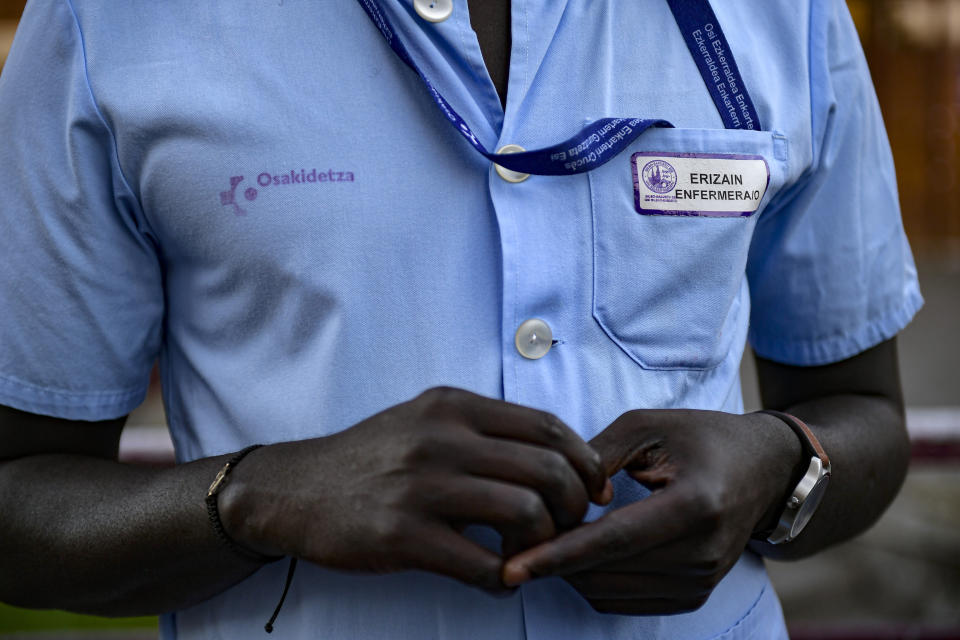 A view of Mbaye Babacar Diouf, in his nurse's uniform at Basurto hospital, in Bilbao, northern Spain, Wednesday, Nov. 18, 2020. Mbaye Babacar Diouf's life as a migrant in Europe took a turn for the better when he was adopted in Spain at the age of 28. That enabled him to pay his debts to human traffickers, study nursing and find a job at a Spanish hospital. Now he's giving back to the community. In a Bilbao hospital he cares for COVID-19 patients. (AP Photo/Alvaro Barrientos)