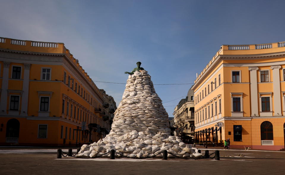 A tall monument in a city plaza is seen covered with sandbags almost to the top. 