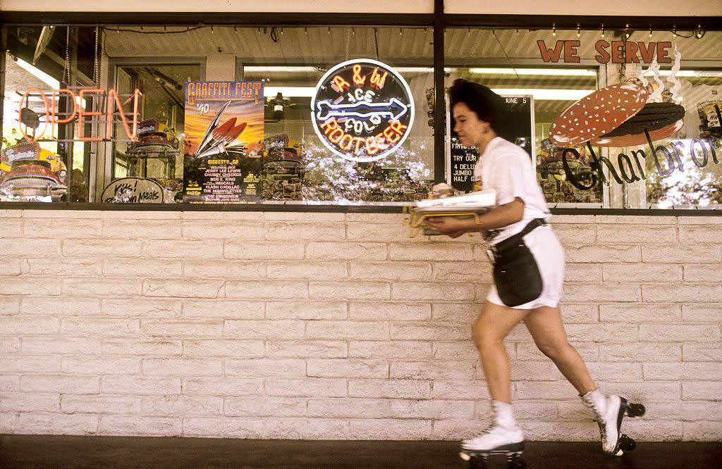 A roller skating waitress delivers an order at a drive-thru restaurant in Modesto, California