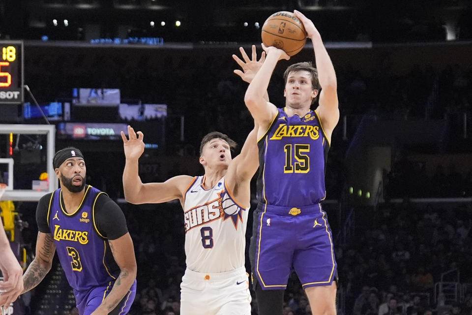 Los Angeles Lakers guard Austin Reaves, right, shoots as Phoenix Suns guard Grayson Allen, center, defends and forward Anthony Davis watches during the first half of an NBA basketball game Thursday, Jan. 11, 2024, in Los Angeles. (AP Photo/Mark J. Terrill)