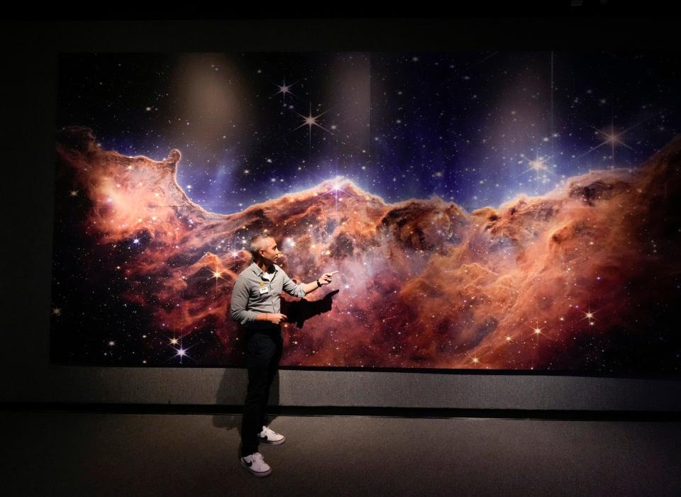 Seth Mayo, curator of science, stands next to an image from the James Webb Space Telescope exhibit at the Museum of Arts and Sciences in Daytona Beach, Thursday, May 25, 2023.