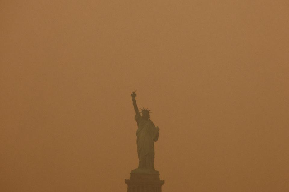 加拿大野火製造的煙霧擴散至美國，紐約的自由女神像6日矗立在一片黃色煙霧中。路透社
