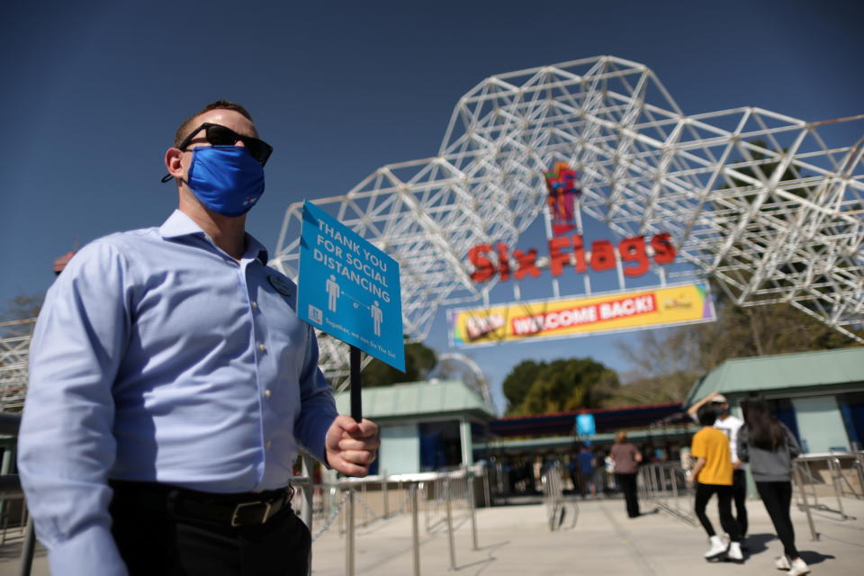 People enter Six Flags Magic Mountain amusement park on the first day of opening, as the coronavirus disease (COVID-19) continues, in Valencia, California, U.S., April 1, 2021. REUTERS/Lucy Nicholson