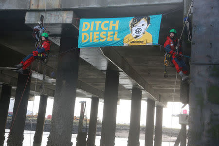 Greenpeace volunteers hang next to a banner after others boarded a ship carrying Volkswagen vehicles for import sailing up the Thames Estuary towards the port of Sheerness, Britain, September 21, 2017. Kristian Buus/Greenpeace handout via REUTERS