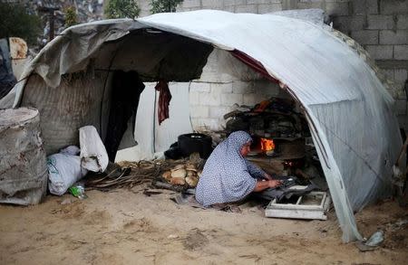 A Palestinian woman bakes bread in a tent outside her dwelling in Khan Younis in the southern Gaza Strip. REUTERS/Ibraheem Abu Mustafa