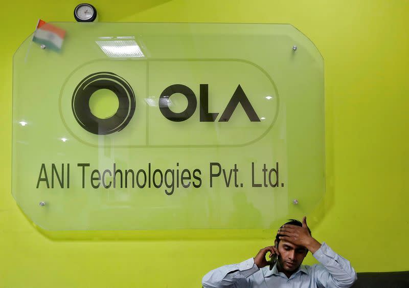 FILE PHOTOAn employee speaks over his phone as he sits at the front desk inside the office of Ola cab service in Gurugram