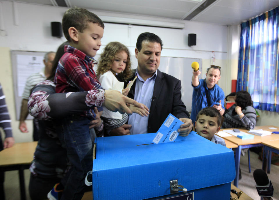 FILE - In this March 17, 2015 file photo, Ayman Odeh, head of the Joint List, an alliance of four small Arab-backed parties accompanied by his family, casts his ballot in Haifa, Israel. Israel's four Arab political parties are announcing a merger ahead of September elections, a move that aims to boost voter turnout among the country's Arab minority. The Palestinian nationalist Balad party announced late Sunday, July 28, 2019, that it would join a reunited Joint List of Arab parties, months after infighting fragmented the political alliance. (AP Photo/Mahmoud Illean, File)