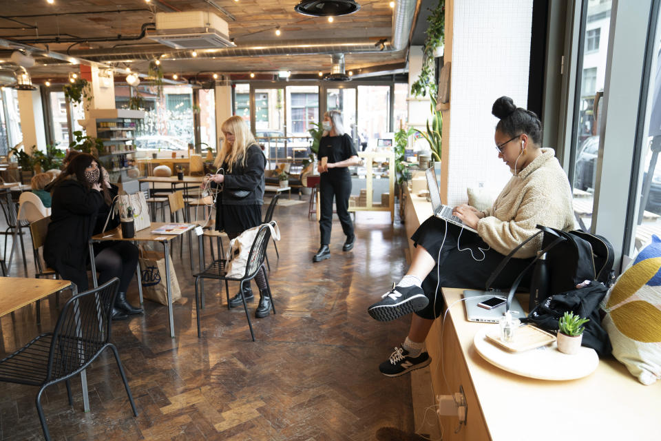 Members of the public sit in a cafe, as pubs, cafes and restaurants in England reopen indoors under the latest easing of the coronavirus lockdown, in Manchester, England, Monday, May 17, 2021. Pubs and restaurants across much of the U.K. are opening for indoor service for the first time since early January even as the prime minister urged people to be cautious amid the spread of a more contagious COVID-19 variant. (AP Photo Jon Super)