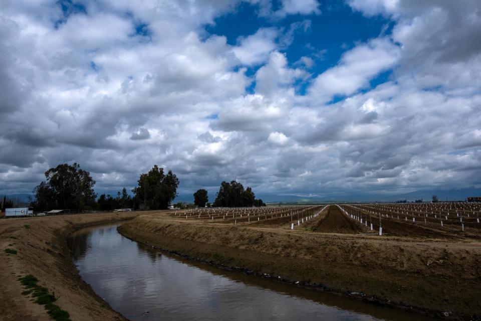 Clouds are reflected in the water of a rural irrigation canal.