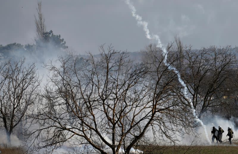 Greek riot police officers walk amid clouds of tear gas near Turkey's Pazarkule border crossing, in Kastanies