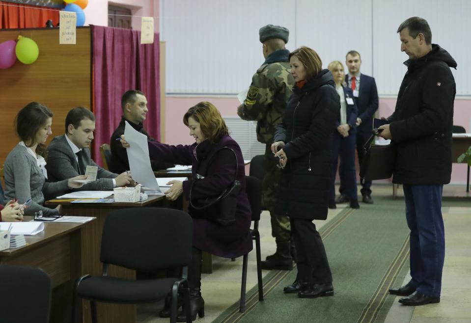 Voters receive their ballot papers a polling station during the parliamentary elections in Minsk, Belarus, Sunday, Nov. 17, 2019. (AP Photo/Sergei Grits)